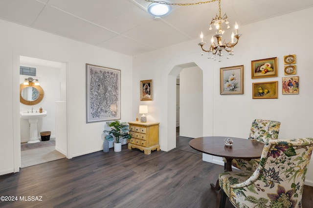 living area featuring arched walkways, dark wood-style flooring, and a notable chandelier