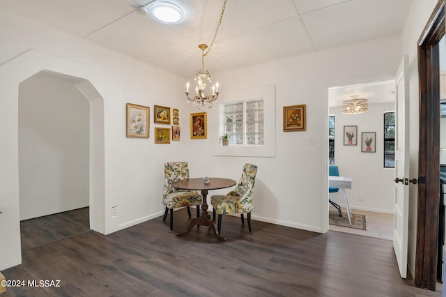 dining space featuring baseboards, arched walkways, dark wood finished floors, and a notable chandelier