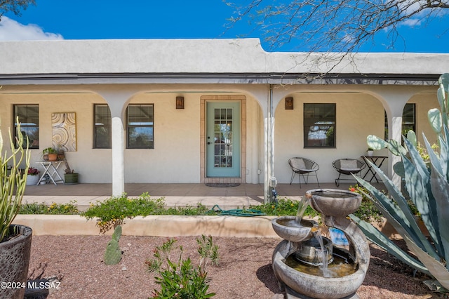 property entrance featuring a porch and stucco siding