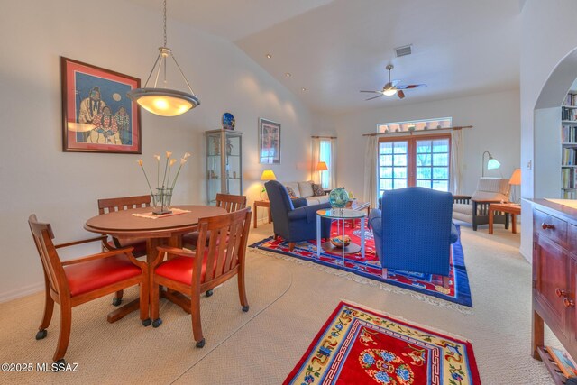 carpeted dining space with visible vents, baseboards, high vaulted ceiling, and ceiling fan