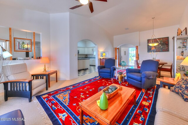 carpeted living area featuring arched walkways and a ceiling fan