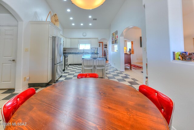 dining area with visible vents, light floors, recessed lighting, arched walkways, and high vaulted ceiling