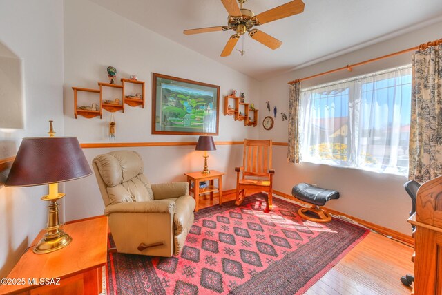 living area with baseboards, a ceiling fan, lofted ceiling, and hardwood / wood-style flooring