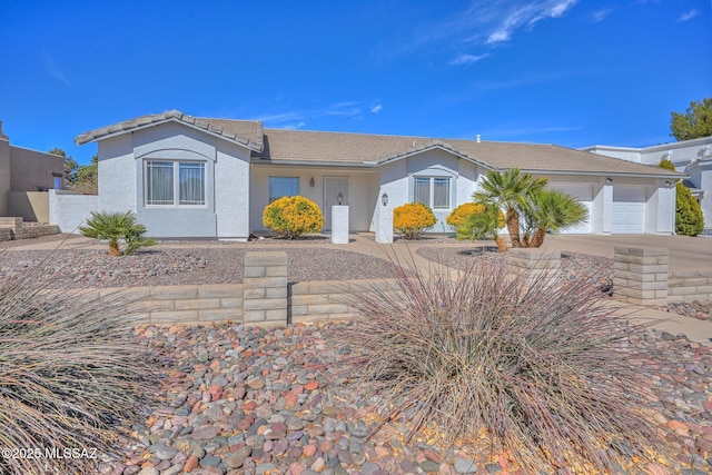 view of front of home featuring a tile roof, a garage, driveway, and stucco siding