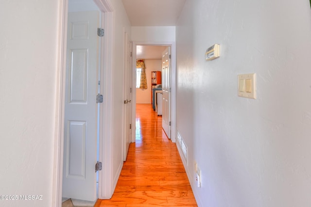 hall with baseboards and light wood finished floors