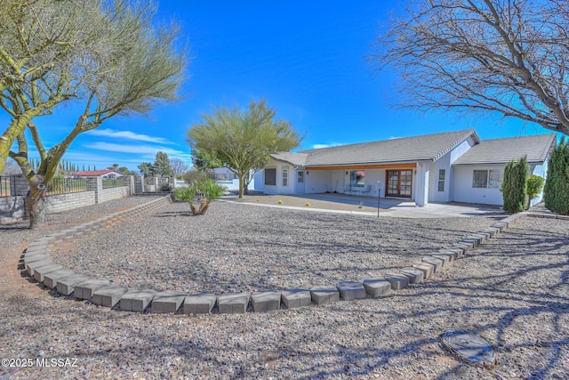 rear view of house with stucco siding and fence