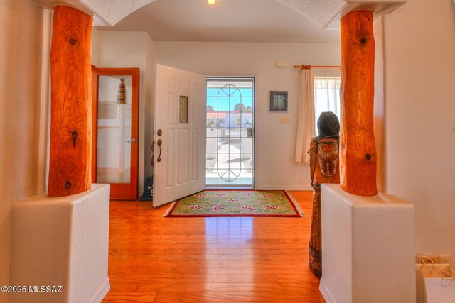 foyer with arched walkways and wood finished floors