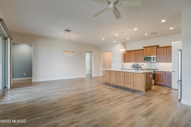 kitchen featuring pendant lighting, stainless steel appliances, a kitchen island with sink, and tasteful backsplash