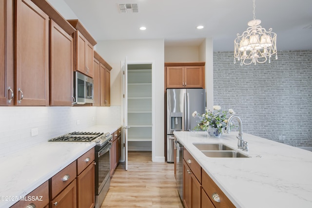 kitchen with sink, light hardwood / wood-style flooring, stainless steel appliances, decorative backsplash, and decorative light fixtures