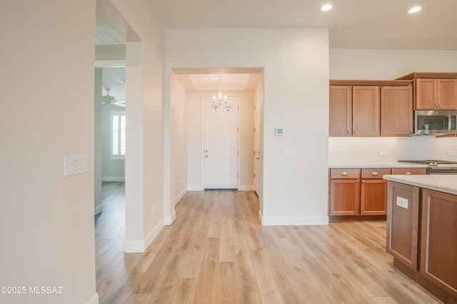 kitchen featuring pendant lighting, range, light hardwood / wood-style floors, and decorative backsplash