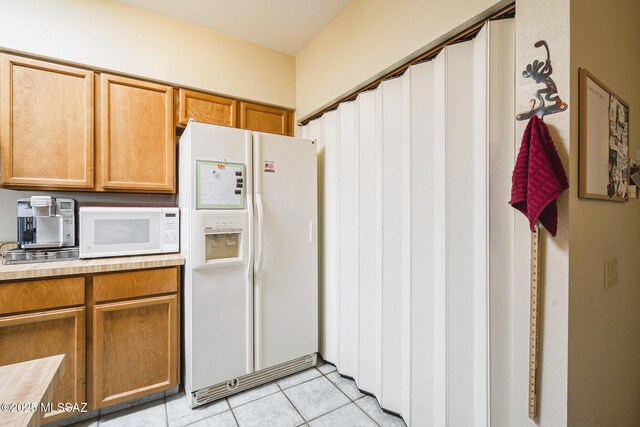 kitchen with white appliances and light tile patterned flooring