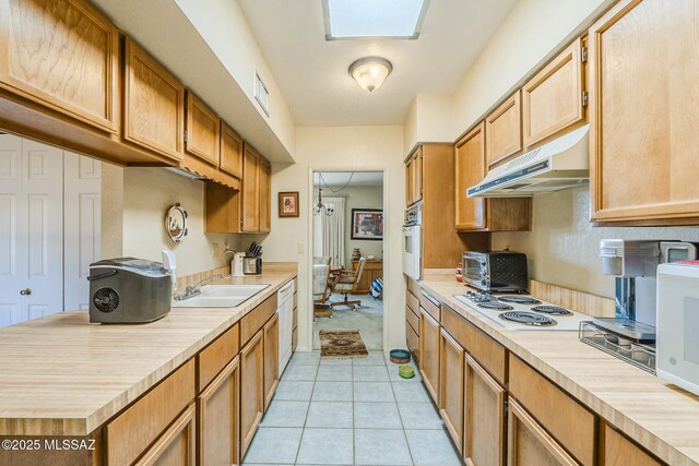 kitchen featuring sink, light tile patterned floors, and white appliances