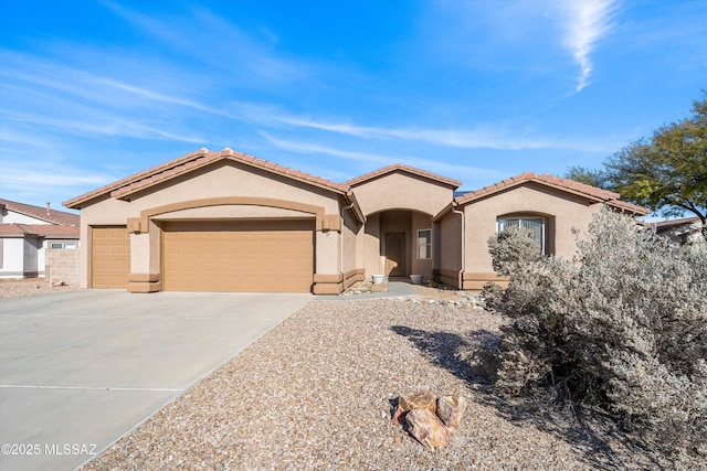 mediterranean / spanish-style home with a garage, a tiled roof, concrete driveway, and stucco siding