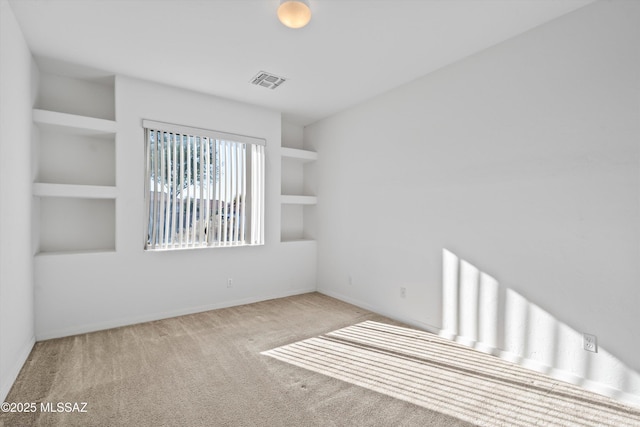 carpeted spare room featuring built in shelves