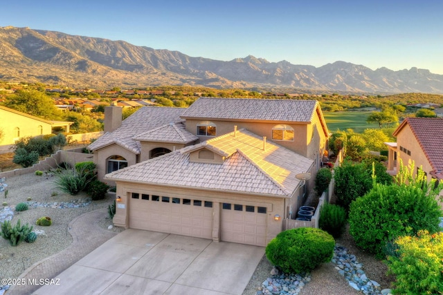 view of front of property with concrete driveway, a mountain view, an attached garage, and stucco siding