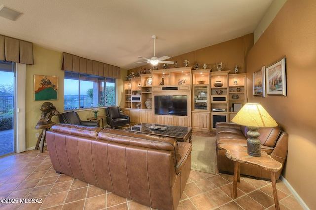 living room with ceiling fan, baseboards, vaulted ceiling, and light tile patterned flooring