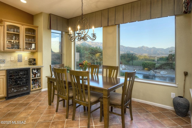 dining area featuring beverage cooler, a bar, plenty of natural light, and a notable chandelier