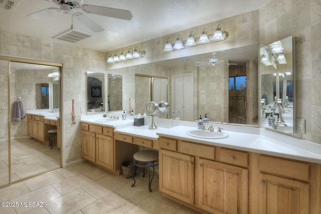 bathroom with a textured ceiling, a stall shower, vanity, and visible vents