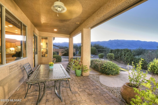 view of patio with outdoor dining area, fence, and a mountain view