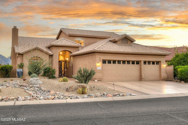 view of front of property featuring a garage, concrete driveway, a tiled roof, and stucco siding