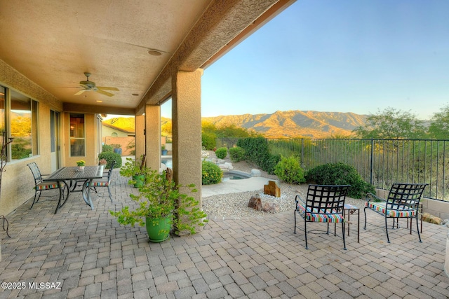 view of patio featuring a fenced backyard, a mountain view, and a ceiling fan