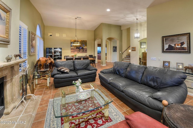 tiled living area with arched walkways, stairway, and a fireplace