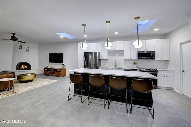 kitchen featuring a center island, light countertops, black fridge with ice dispenser, open floor plan, and stainless steel range with electric cooktop