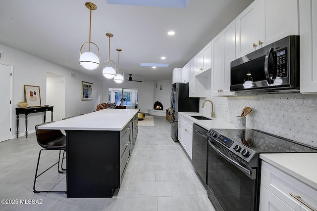 kitchen featuring a center island, light countertops, white cabinetry, a sink, and black appliances