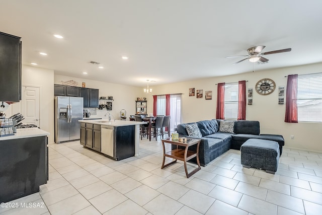 kitchen with sink, light tile patterned floors, ceiling fan, appliances with stainless steel finishes, and a kitchen island with sink