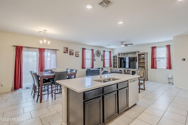 kitchen featuring pendant lighting, sink, light tile patterned floors, a center island with sink, and stainless steel dishwasher