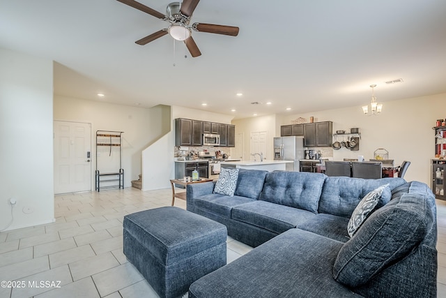 living room with ceiling fan with notable chandelier and light tile patterned floors