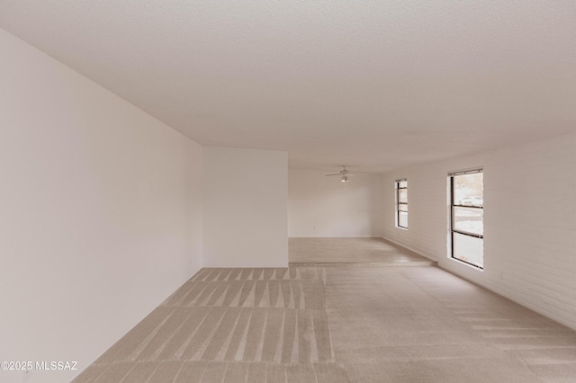 spare room featuring a textured ceiling, a ceiling fan, and light colored carpet