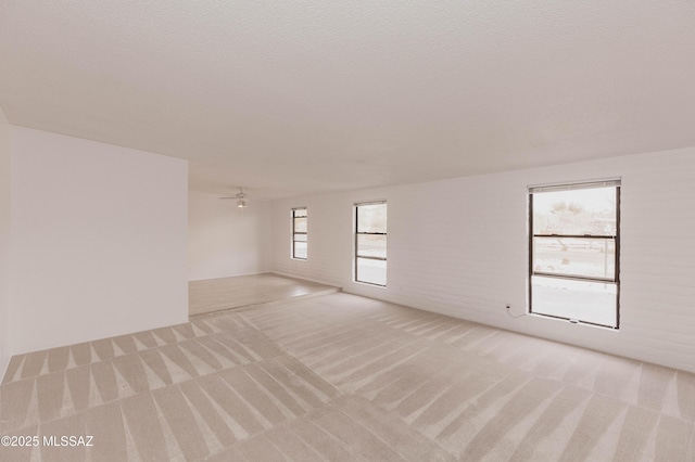 spare room featuring brick wall, a textured ceiling, and light colored carpet