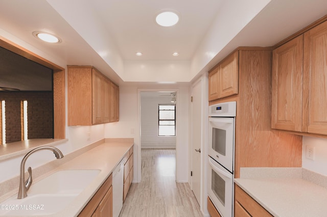 kitchen featuring white appliances, light wood-style floors, light countertops, and a sink