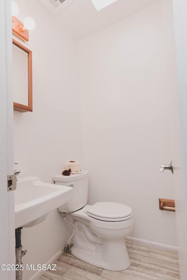 bathroom featuring baseboards, visible vents, toilet, and wood finished floors