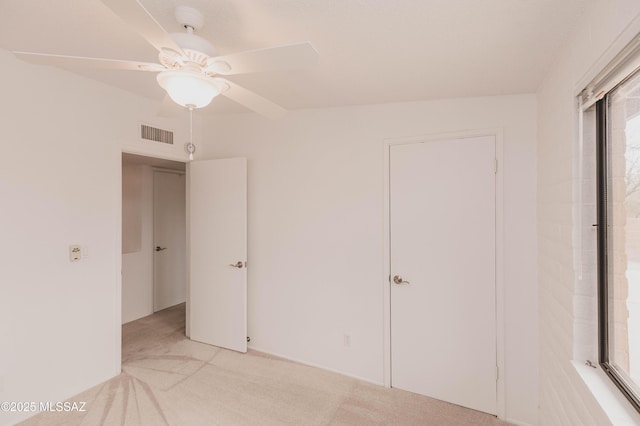 unfurnished bedroom featuring ceiling fan, visible vents, and light colored carpet