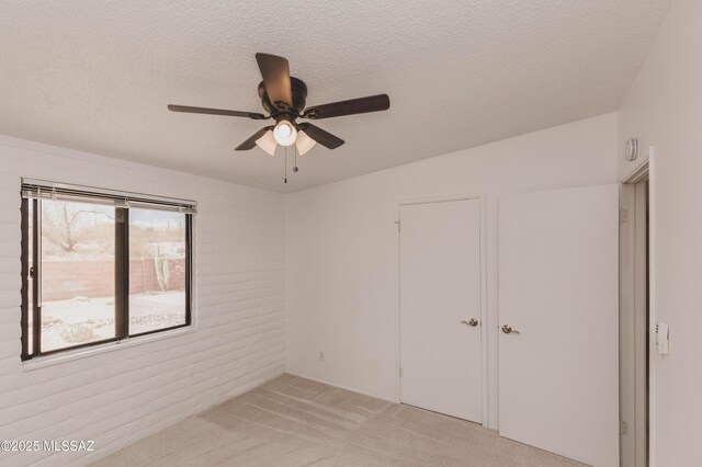 unfurnished room with a ceiling fan, light carpet, and a textured ceiling