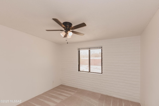 spare room featuring light carpet, ceiling fan, and a textured ceiling