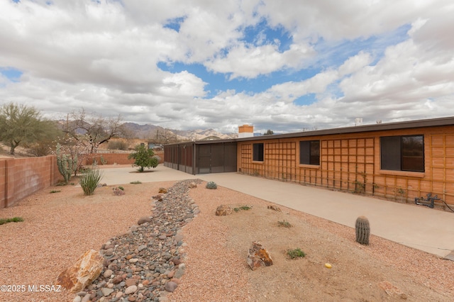 exterior space featuring a sunroom, a patio area, a fenced backyard, and driveway