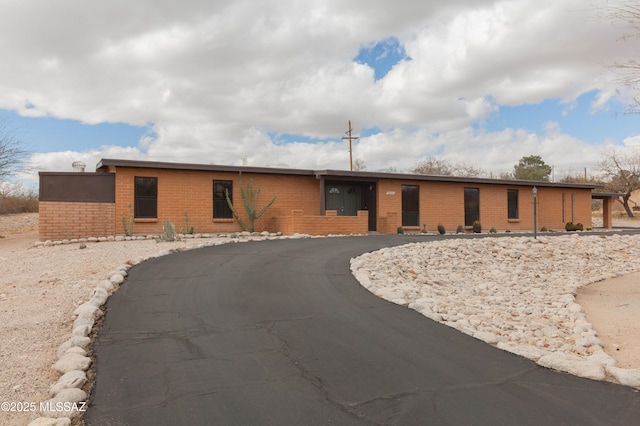 ranch-style house featuring aphalt driveway and brick siding