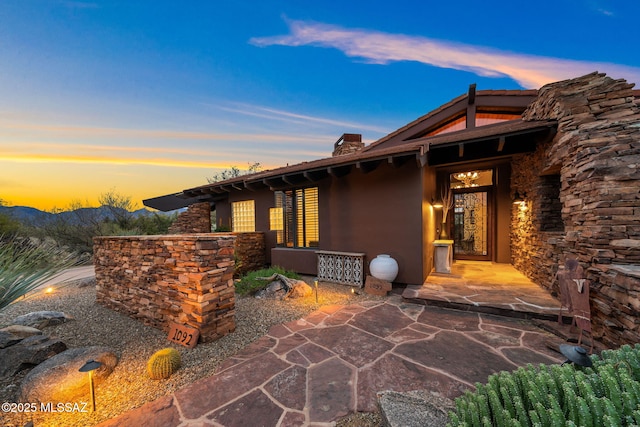 exterior entry at dusk featuring a patio