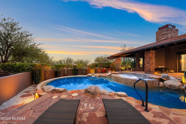 pool at dusk featuring an in ground hot tub