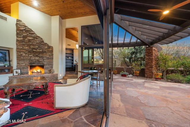 patio terrace at dusk with a pergola and an outdoor stone fireplace