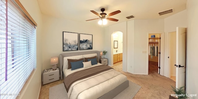 bedroom featuring ensuite bathroom, a spacious closet, light colored carpet, ceiling fan, and a closet