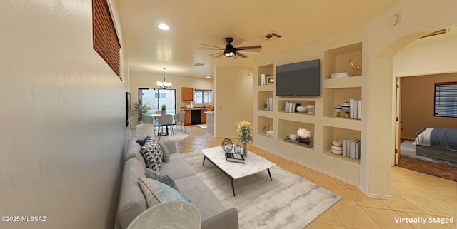 living room featuring built in shelves, ceiling fan with notable chandelier, and light tile patterned floors