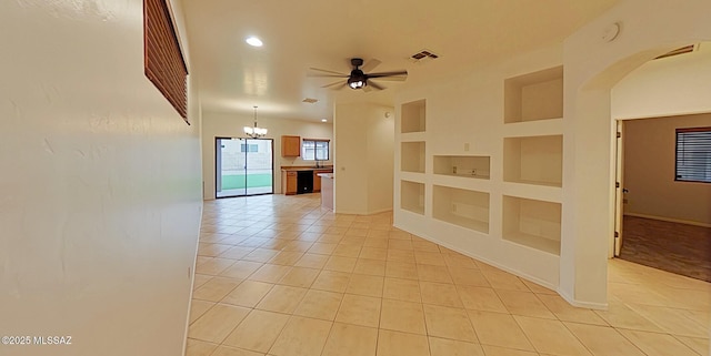 tiled empty room featuring ceiling fan with notable chandelier and built in shelves