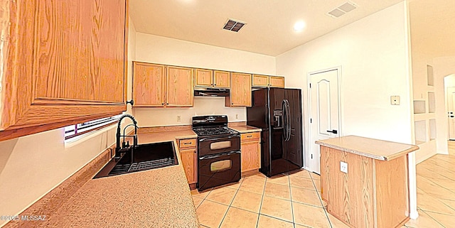 kitchen with light tile patterned flooring, sink, light stone counters, and black appliances