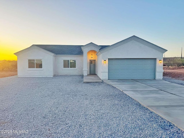 ranch-style home with an attached garage, driveway, and stucco siding