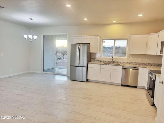 kitchen with a sink, light stone counters, stainless steel appliances, and a wealth of natural light