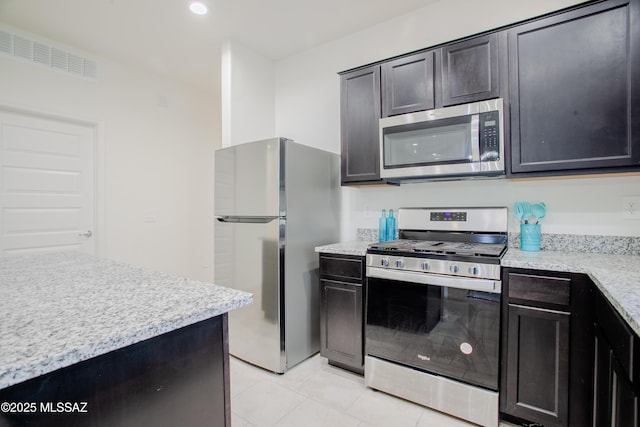 kitchen with light stone counters, light tile patterned floors, and stainless steel appliances